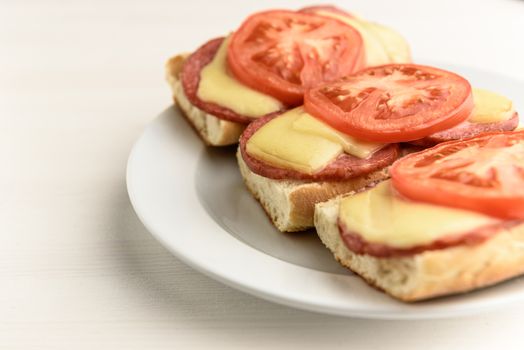 hot sandwiches with melted cheese sausage, salami and tomatoes
