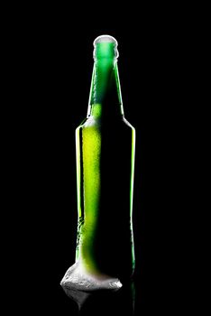 beer bottle opened with resultant beer and foam on black background with reflection