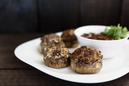 baked mushrooms with meat and sauce on a plate and wood