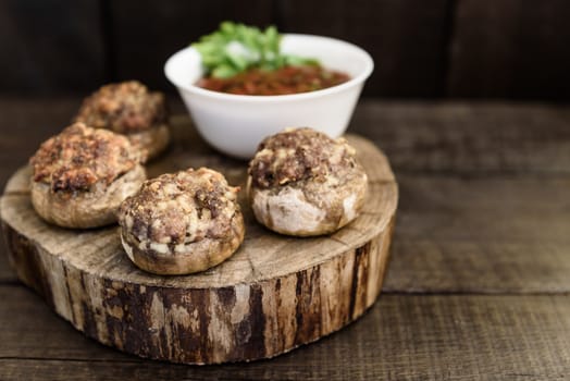 baked mushrooms with meat and sauce on a wood