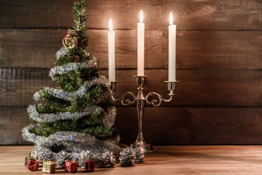 Christmas decorative tree is adorned with rain stands on the table with lit candles