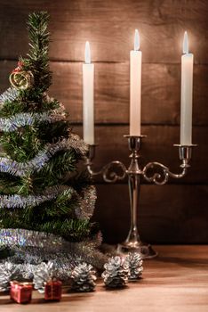 Christmas decorative tree is adorned with rain stands on the table with lit candles