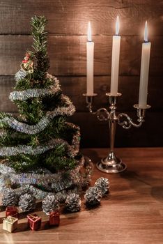 Christmas decorative tree is adorned with rain stands on the table with lit candles