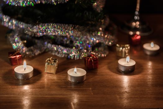 Christmas decorative tree is adorned with rain stands on the table with lit candles