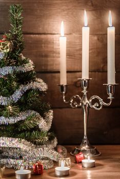 Christmas decorative tree is adorned with rain stands on the table with lit candles