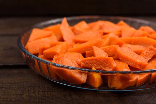 sweet baked pumpkin chopped lomikami in glass dish on wooden background