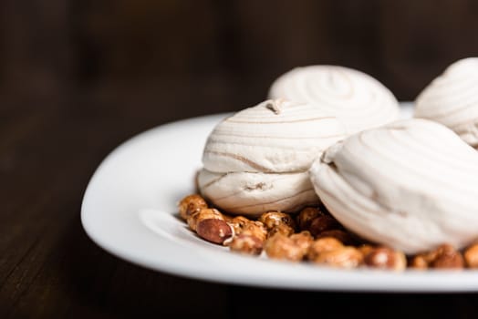 white marshmallows and sweet peanuts on the plate and wood