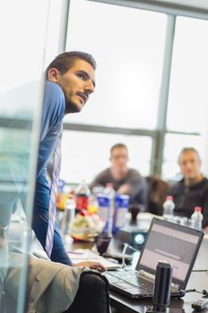 Business man making a presentation at office. Business executive delivering a presentation to his colleagues during meeting or in-house business training, explaining business plans to his employees.