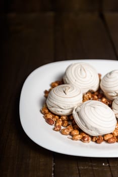 white marshmallows and sweet peanuts on the plate and wood