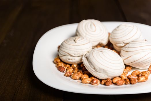 white marshmallows and sweet peanuts on the plate and wood