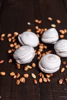 white marshmallows and sweet peanuts on the plate and wood