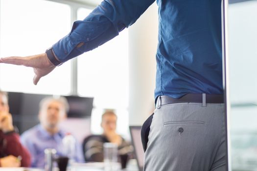 Business man making a presentation at office. Business executive delivering a presentation to his colleagues during meeting or in-house business training. Rear view. Business and entrepreneurship.