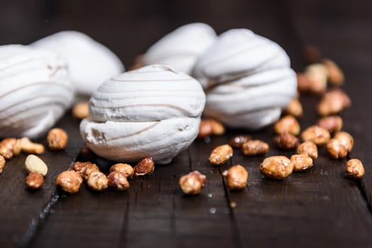 white marshmallows and sweet peanuts on the plate and wood