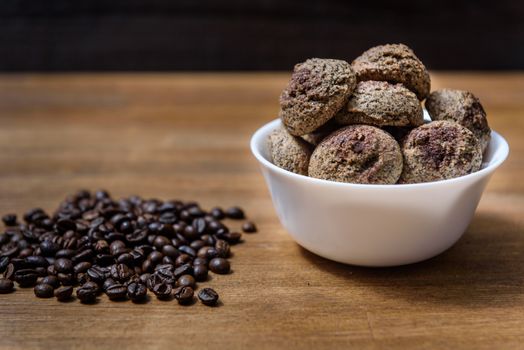 coffee cookies in a white plate with coffee beans on wooden brown table