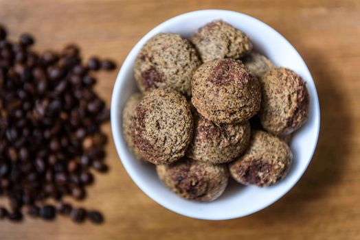 coffee cookies in a white plate with coffee beans on wooden brown table