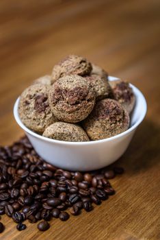 coffee cookies in a white plate with coffee beans on wooden brown table