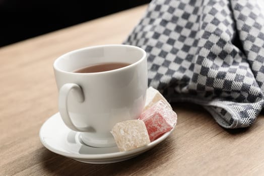 delight yellow and red on a plate sprinkled with powdered sugar with tea in a Cup