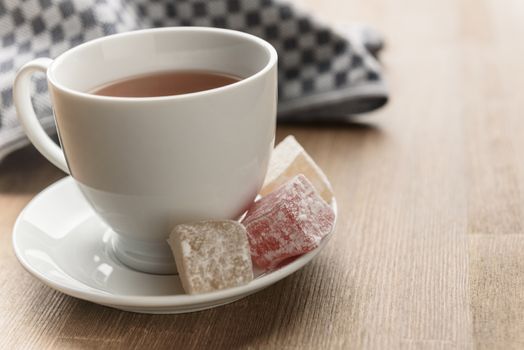 delight yellow and red on a plate sprinkled with powdered sugar with tea in a Cup