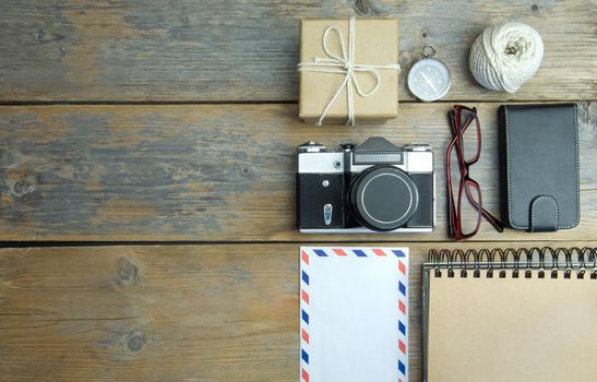 Camera, international envelope, hat and compass over a wooden  background with space