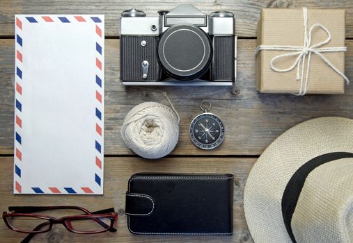 Camera, envelope, hat and compass over a wooden  background