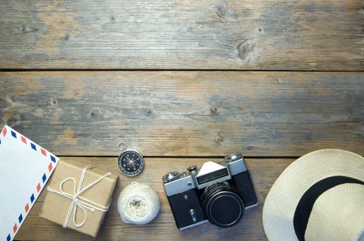 Camera, international envelope, hat and compass over a wooden  background with space