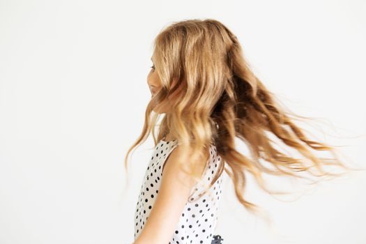 Lovely little girl in a polka-dot dress against a white background. Happy kids