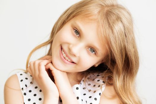 Closeup portrait of a lovely smiling little girl in front of white background
