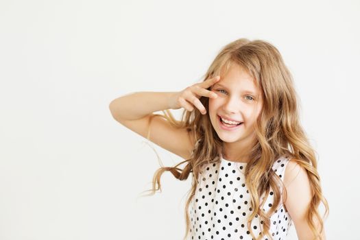 Lovely frisky little girl in a polka-dot dress against a white background. Happy kids