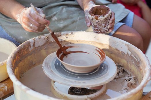 Hands of girl potter, creating an earthen jar on the circle, close-up