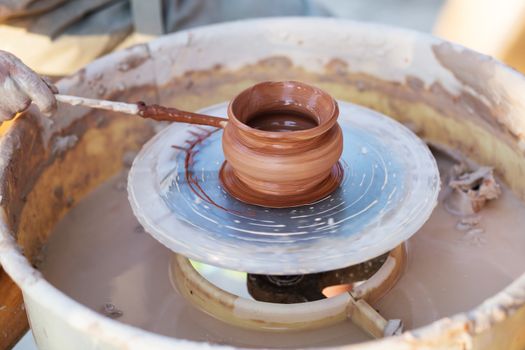 Hands of young potter, creating an earthen jar on the circle, close-up