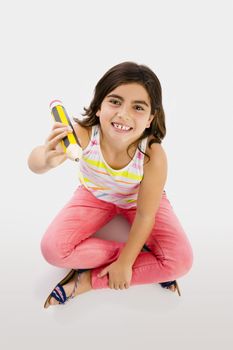 Little girl making a drawing with a big pencil in the floor