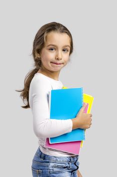 Smiling little student girl holding notebooks