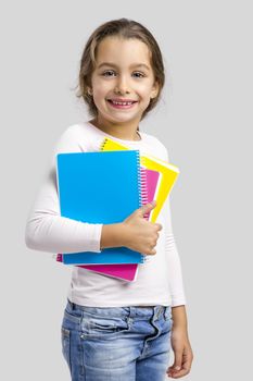 Smiling little student girl holding notebooks