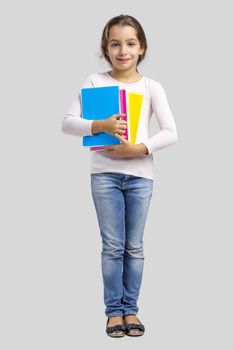 Smiling little student girl holding notebooks