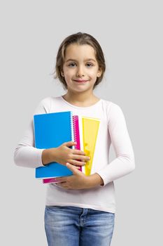 Smiling little student girl holding notebooks