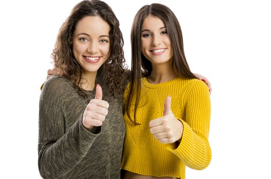 Studio portrait of two beautiful girls with thumbs up