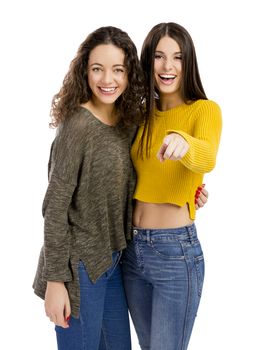 Studio portrait of two beautiful girls pointing and looking to the camera