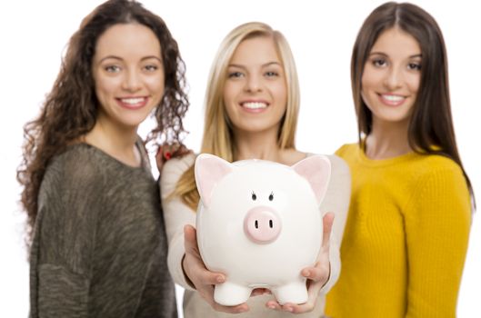 Studio portrait of three teenage girls holding a piggybank