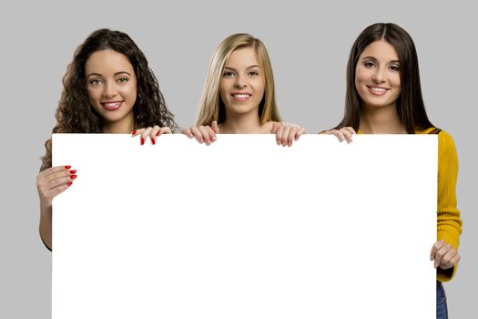 Studio portrait of three girls holding and showing something on a cardboard