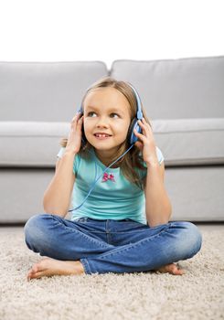 Little blonde girl at home listen music with headphones