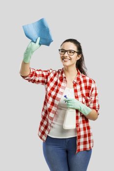 Pretty woman wearing gloves, using a cleaning spray and cleaning the house