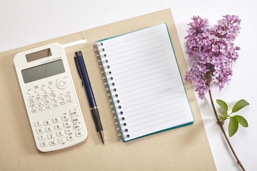 Top view office workplace - calculator, pen, flower and notebook on white table