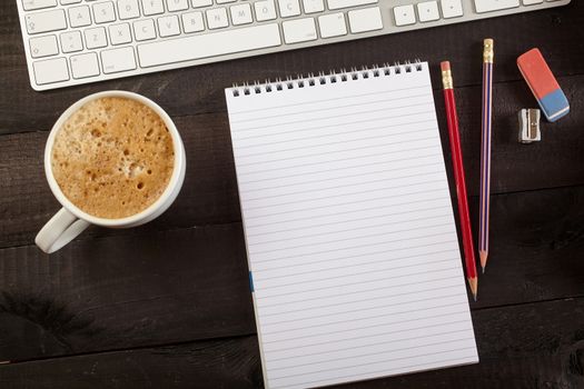 Top view office workplace - coffee, keyboard, pencil and notebook on black table