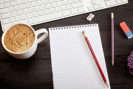 Top view office workplace - coffee, keyboard, pencil, flower and notebook on black table