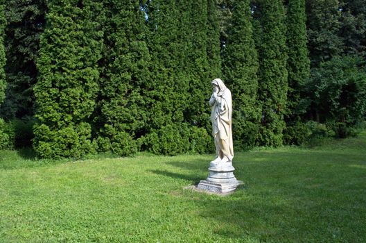 Marble park sculpture of an old man freezing and wrapped into coverlets personifying the cold season of the year. The palace and park complex Manor Tarnowski, s.Kachanovka, Ukraine