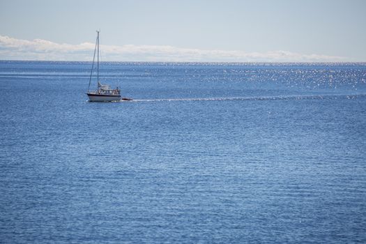 Sailboat on Ocean with a partly cloudy sky.