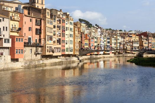 GIRONA, SPAIN - MAY 15, 2016 :Colorful houses on the river Onyar and tourists on the Princess Bridge.  Girona is one of the major Catalan cities.It has one of the largest historical Jewish quarters in Europe.