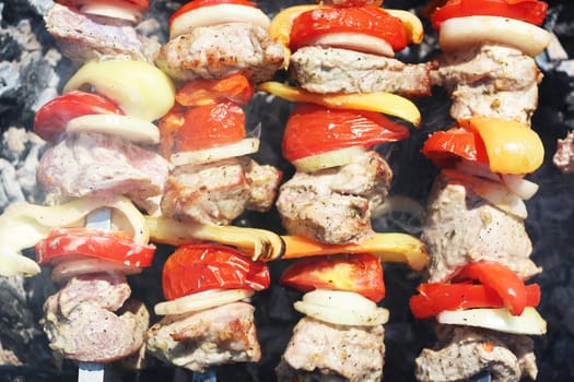 The barbecue cooking. Meat and vegetables tomato, bow, pepper, grilled on charcoal, close-up