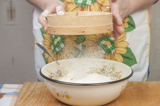 Women's hands preparing flour before baking pie.