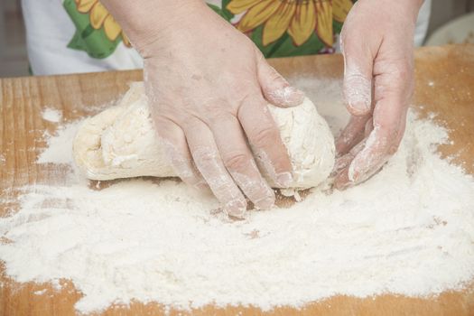 Women's hands preparing fresh yeast dough on wooden table